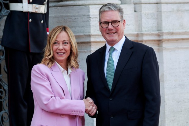 a woman in a pink jacket shakes hands with a man in a suit