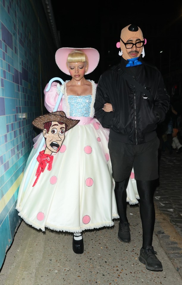 a man in a black jacket stands next to a woman in a toy story costume