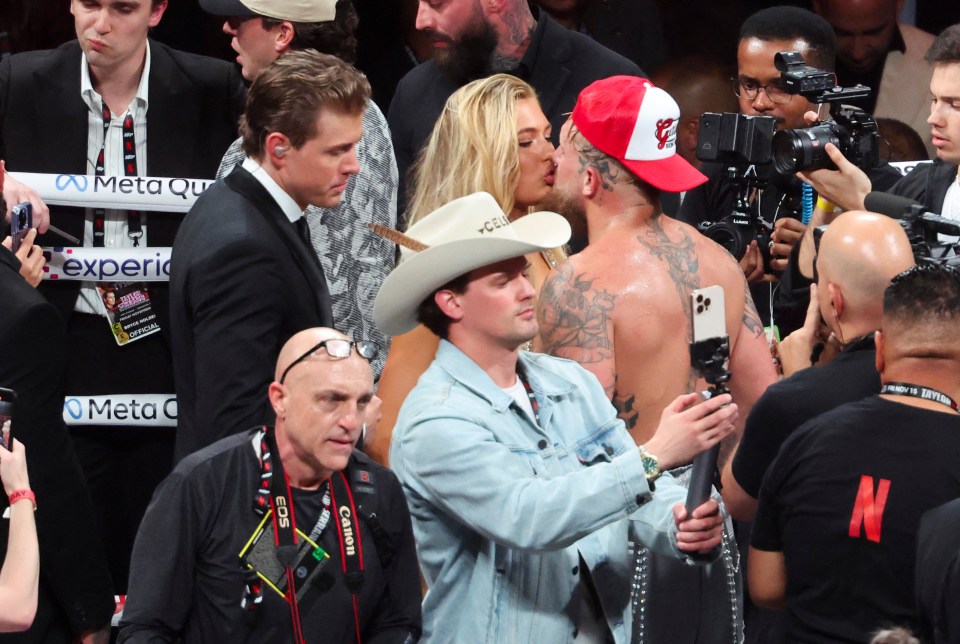 a man in a cowboy hat is taking a picture of a woman kissing a man