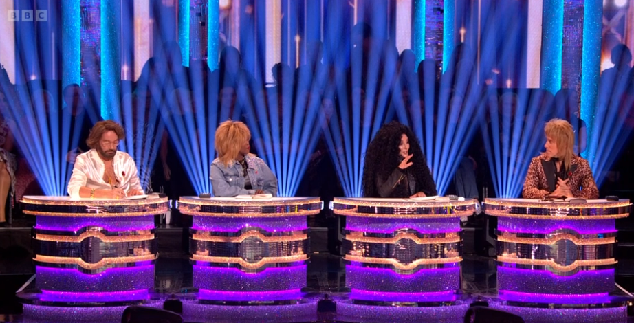 four people are sitting at a table with a bbc logo in the background