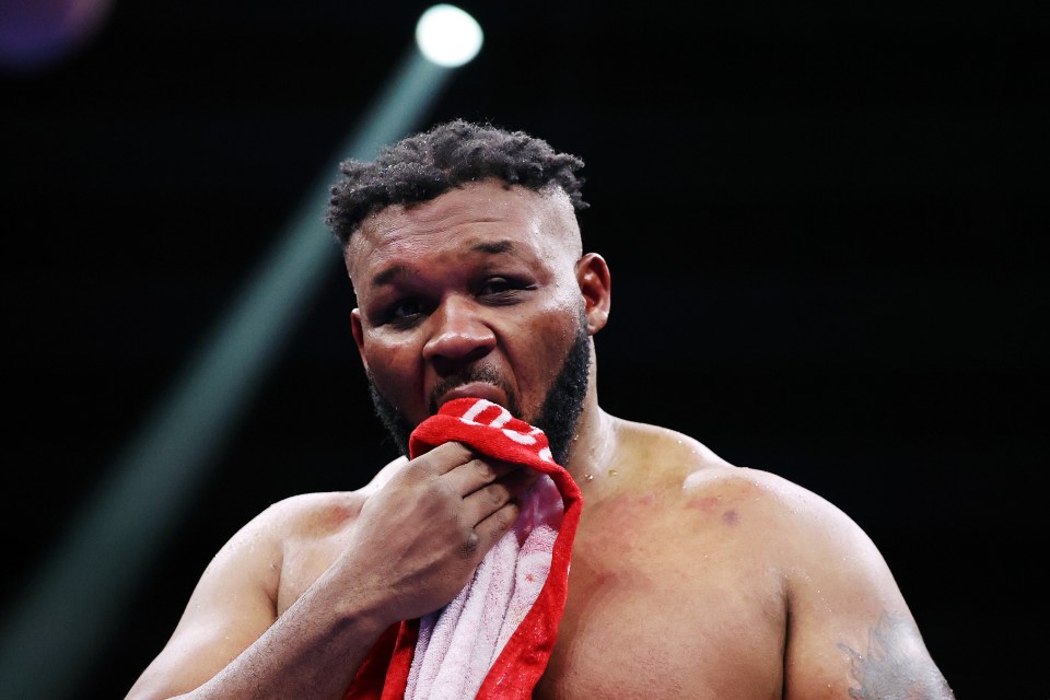 a boxer wipes his face with a red and white towel with the letter l on it