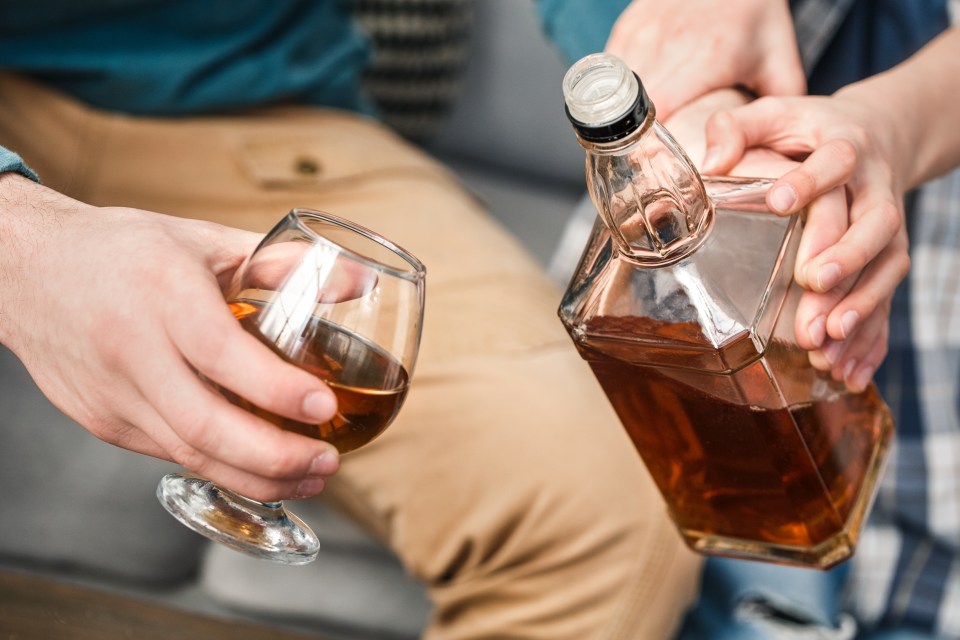 Boy and father alcoholic at home son stopping dad fron drinking whiskey hands close-up