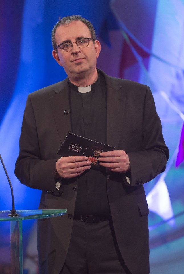 a man in a black suit holds a book that says ' british comedy awards ' on it