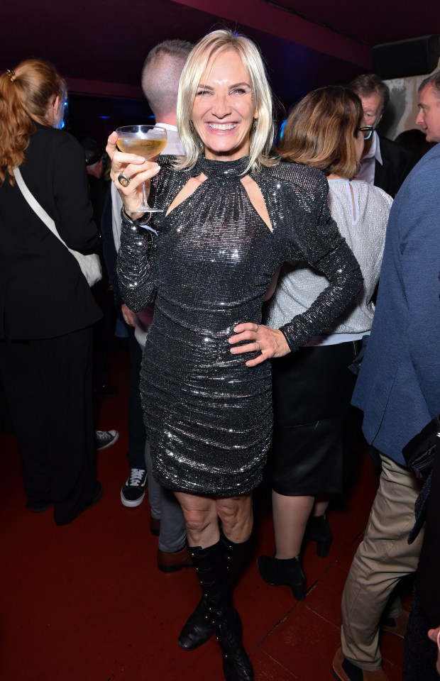 a woman in a black dress is holding a glass of wine