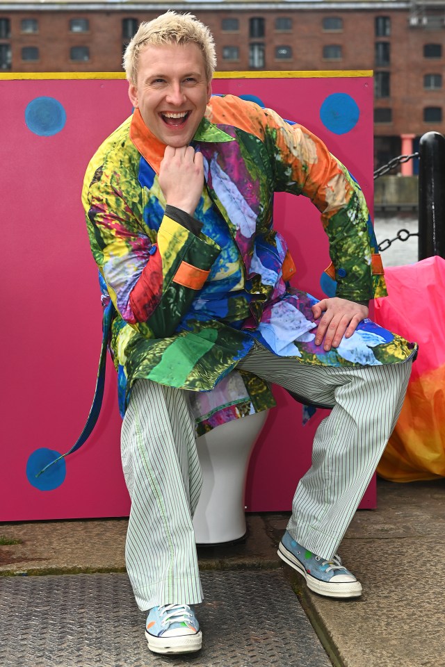 a man in a colorful coat sits on a toilet