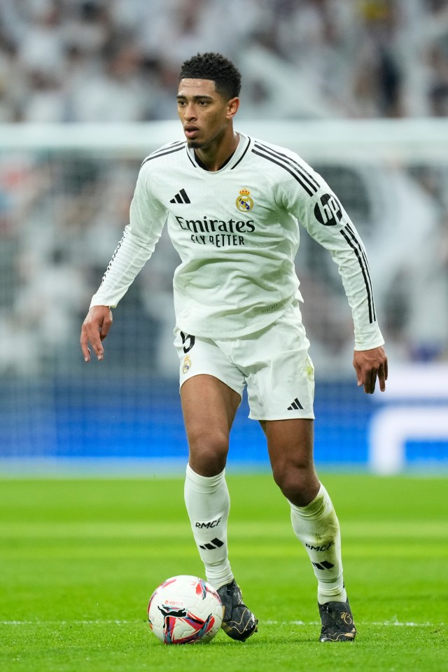 a soccer player wearing a white emirates jersey runs with the ball