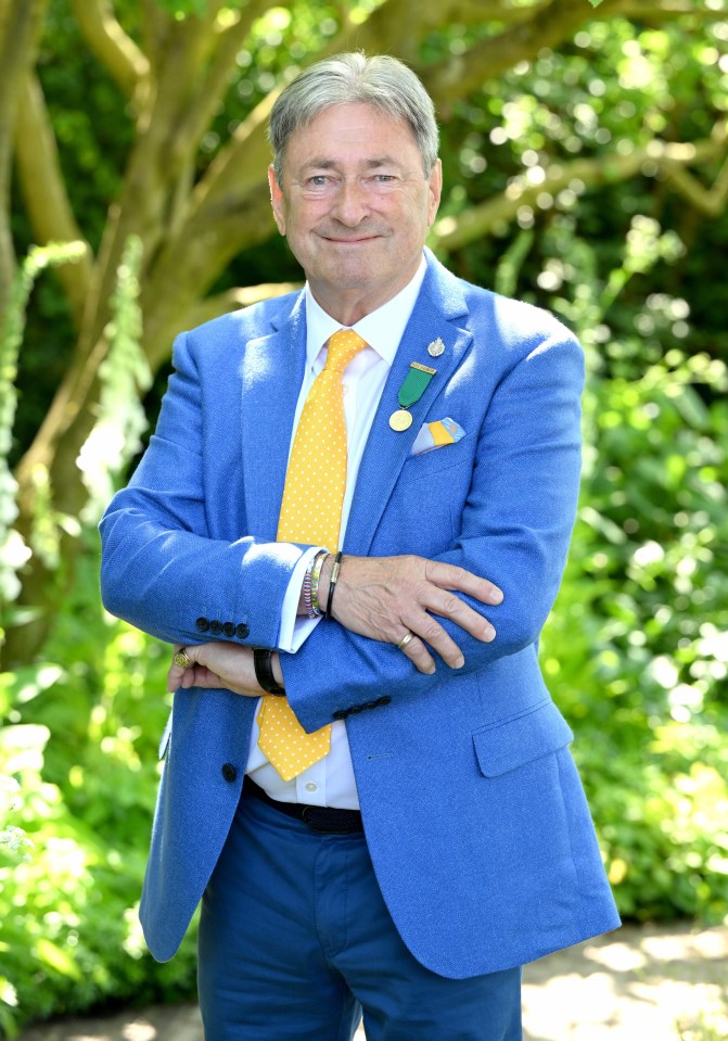 a man in a blue suit and yellow tie stands with his arms crossed