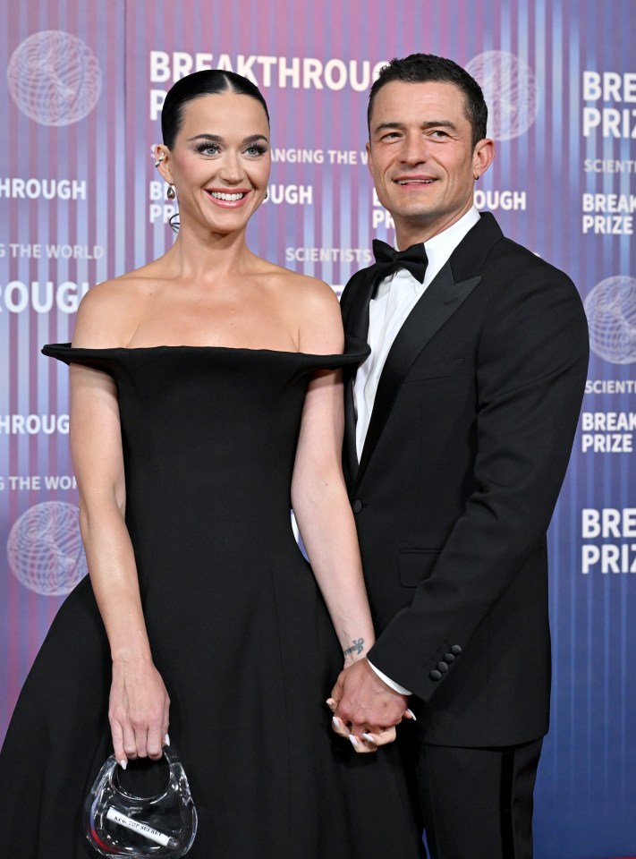 a man and a woman hold hands in front of a wall that says breakthrough