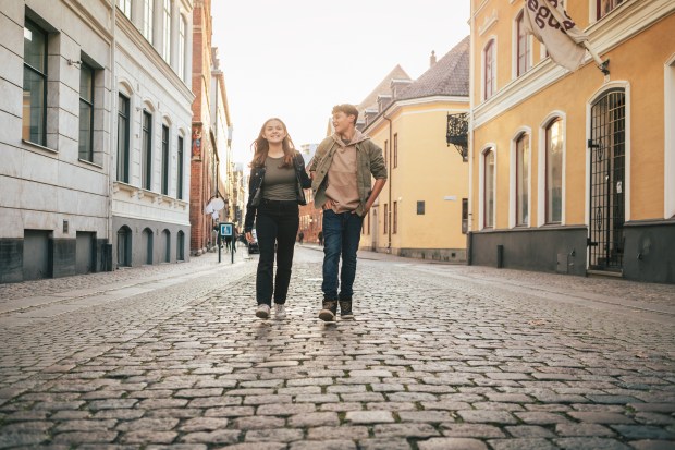 a man and a woman are walking down a cobblestone street