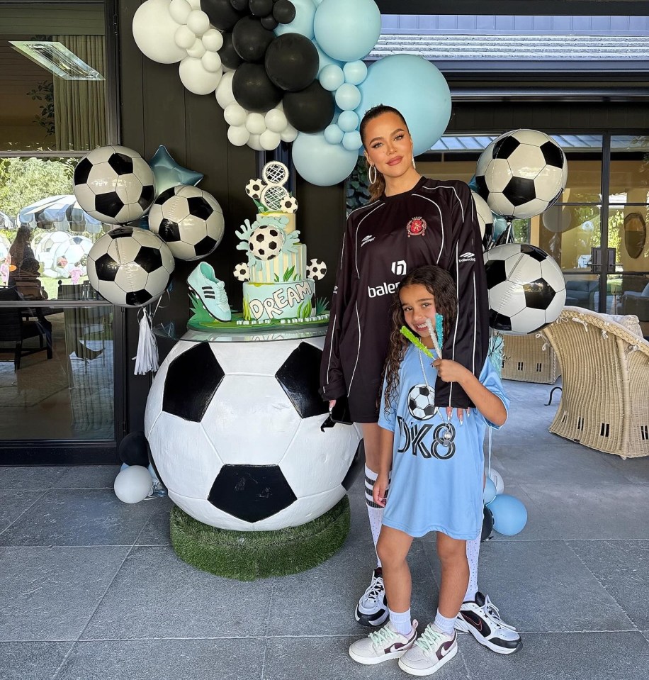 a woman in a soccer jersey stands next to a little girl