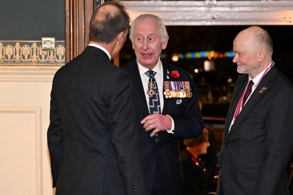 a man with medals on his jacket talks to two other men