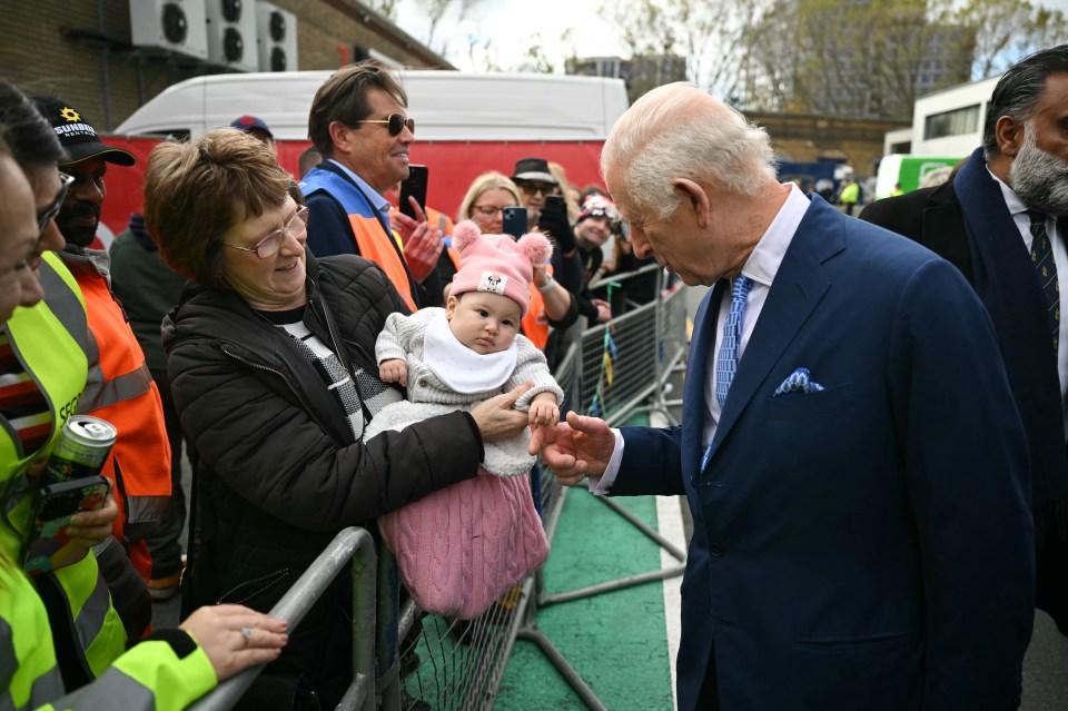 a man in a suit talks to a woman holding a baby