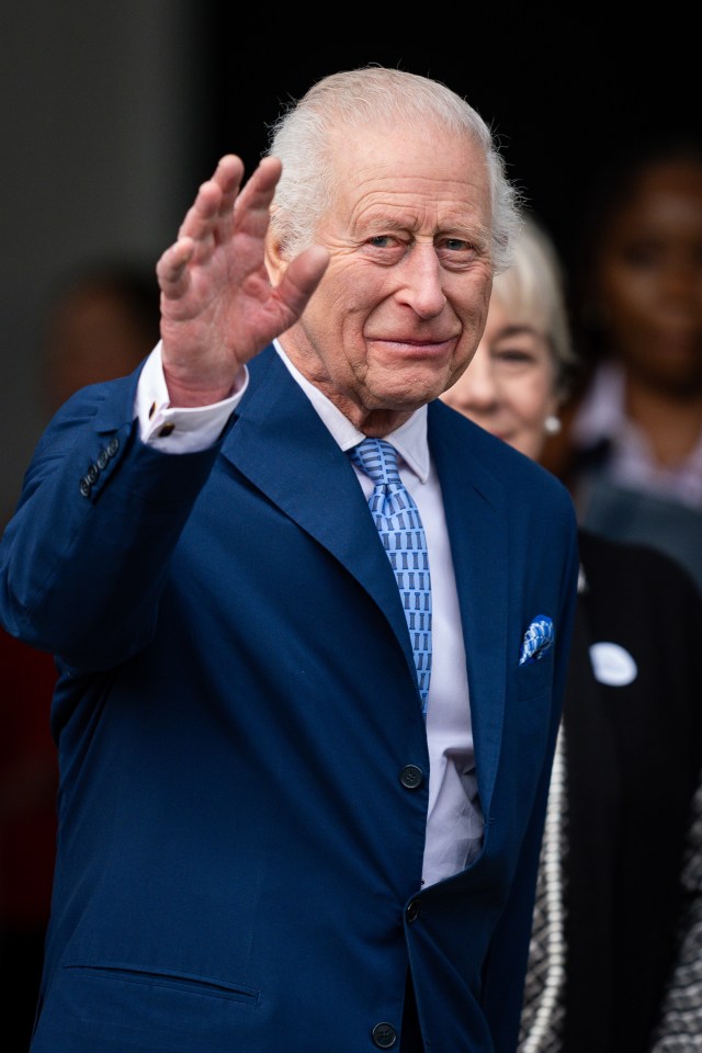 a man in a blue suit and tie is waving