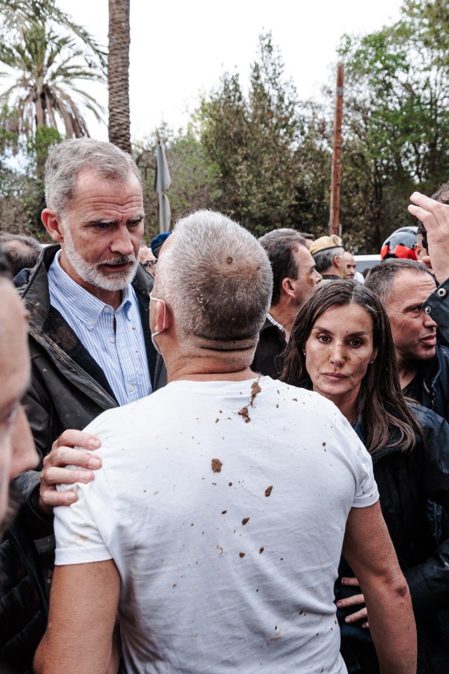 a man with a shaved head stands in a crowd while a woman looks on