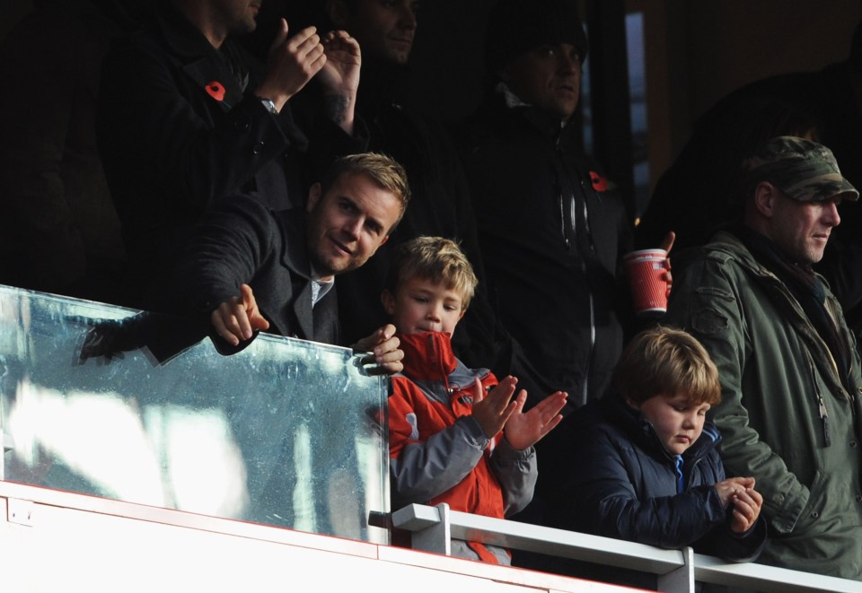 a boy in an orange jacket applauds in the stands