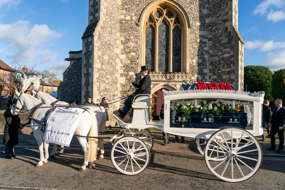 a white horse drawn carriage carrying a funeral casket