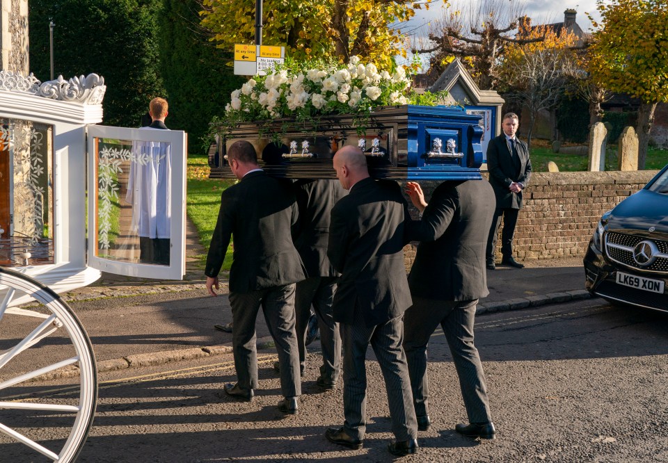 a black coffin is being carried down the street by men