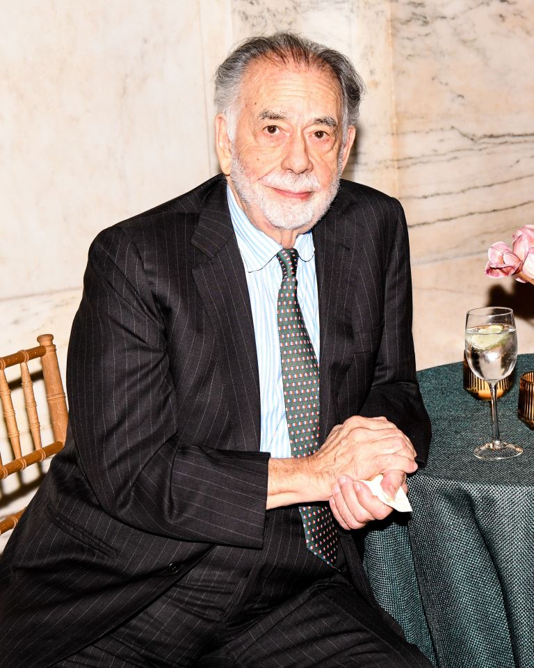 a man in a suit and tie sits at a table with a glass of water