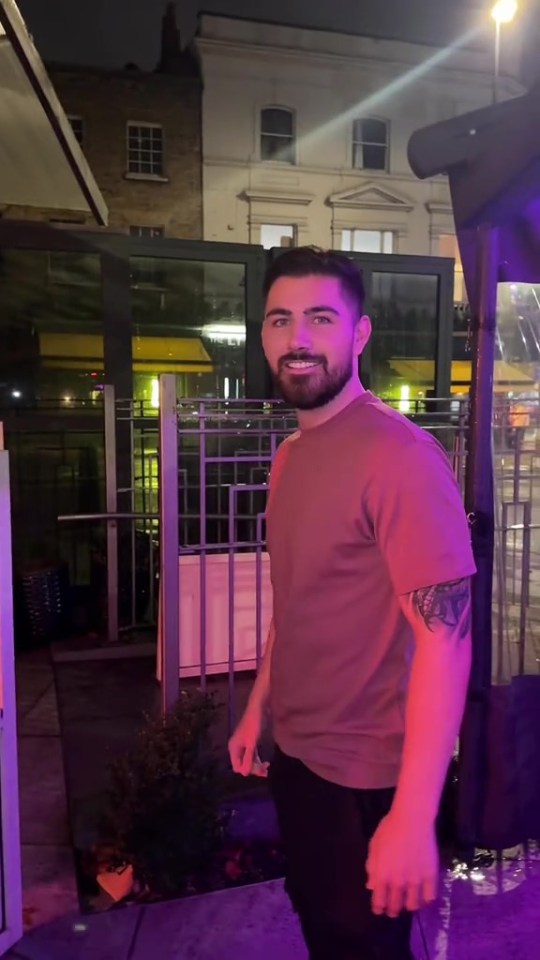 a man with a tattoo on his arm is standing in front of a building