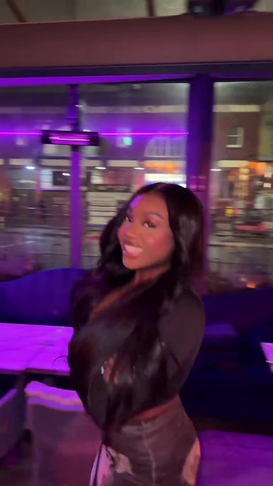 a woman is standing in front of a purple light in a restaurant .