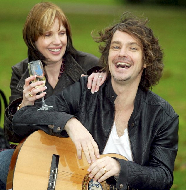 a man with a guitar and a woman holding a glass of wine