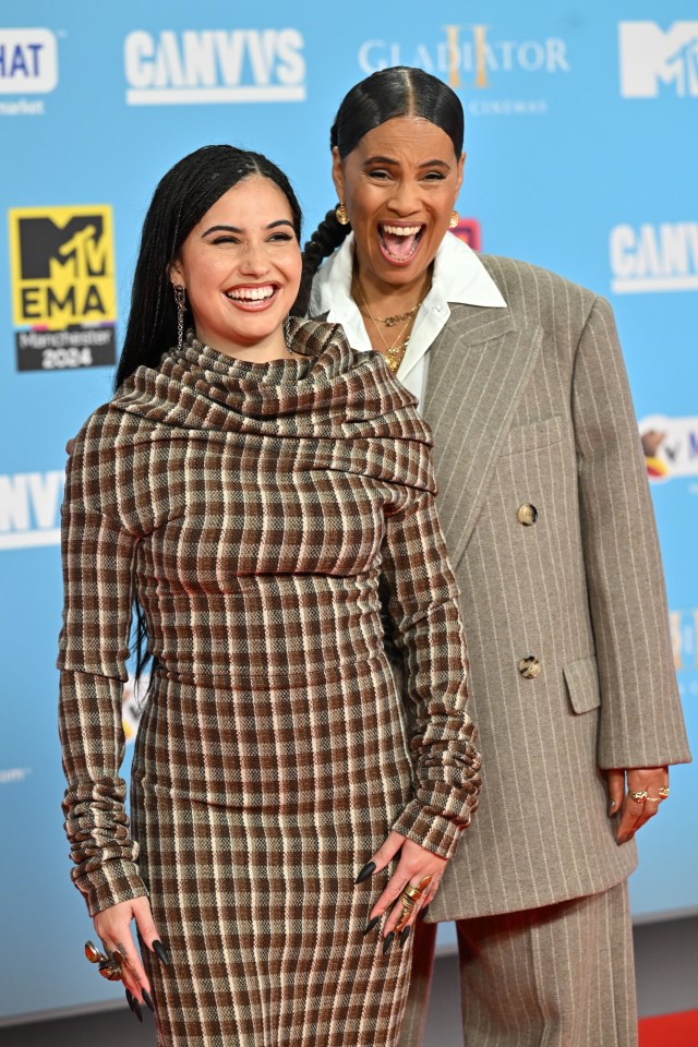 two women stand on a red carpet in front of a sign that says canvvs