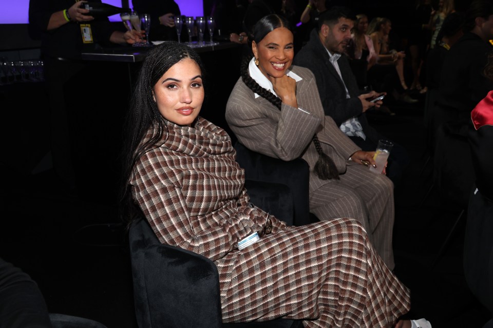 a woman in a plaid dress sits next to another woman in a suit