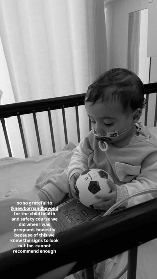 a baby in a hospital bed holding a soccer ball