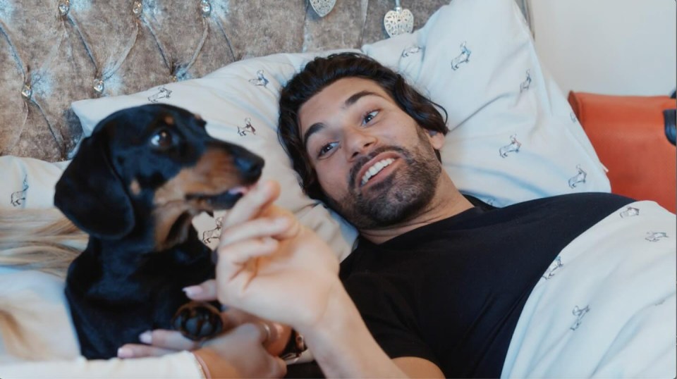 a man laying in bed with a dog on his lap