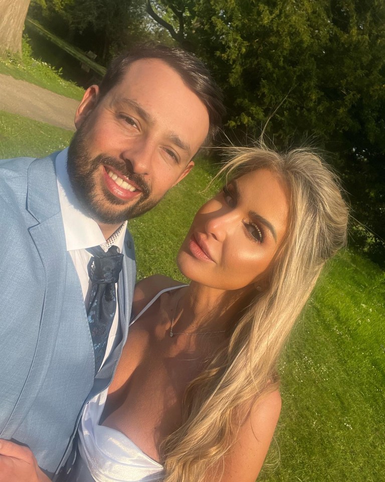 a man and woman posing for a picture in a park