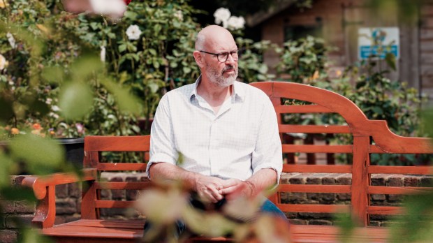 a man sits on a bench in front of a sign that says eco