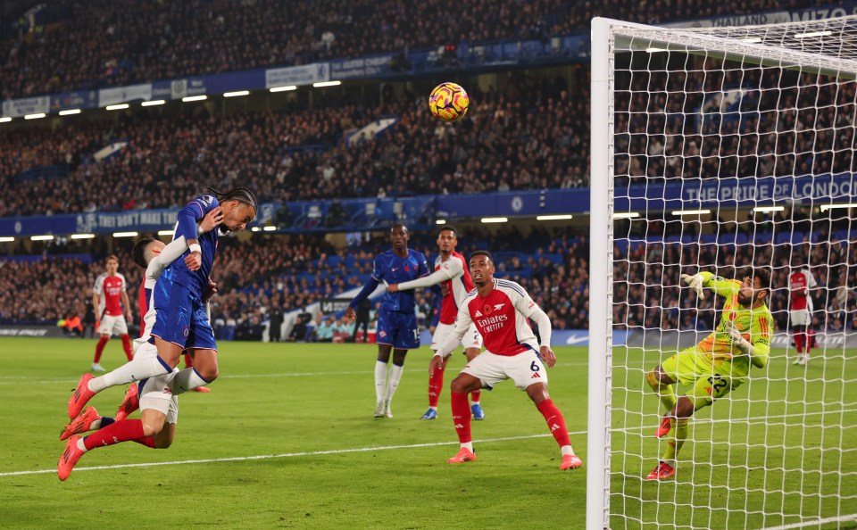 a soccer player wearing a fly emirates jersey kicks the ball into the goal