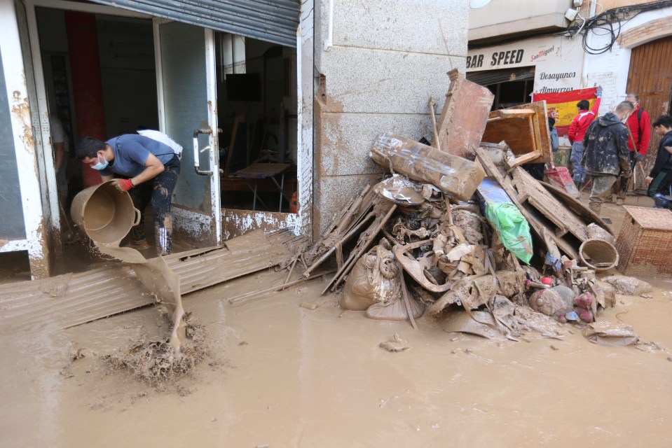 A man pours muddy water out of the entrance of a building after floods in Paiporta