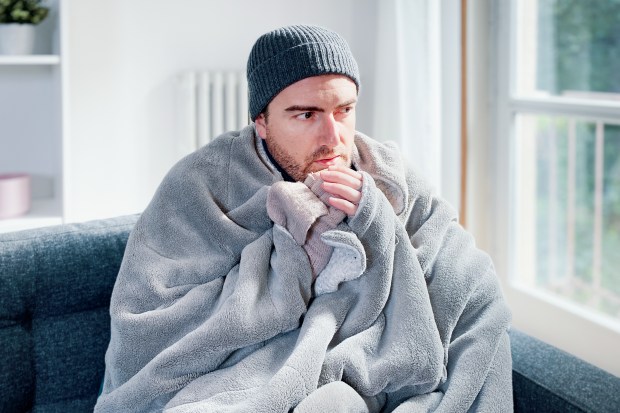 a man wrapped in a blanket is sitting on a couch