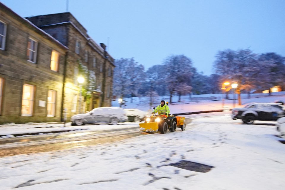 a man is driving a snow plow down a snowy street