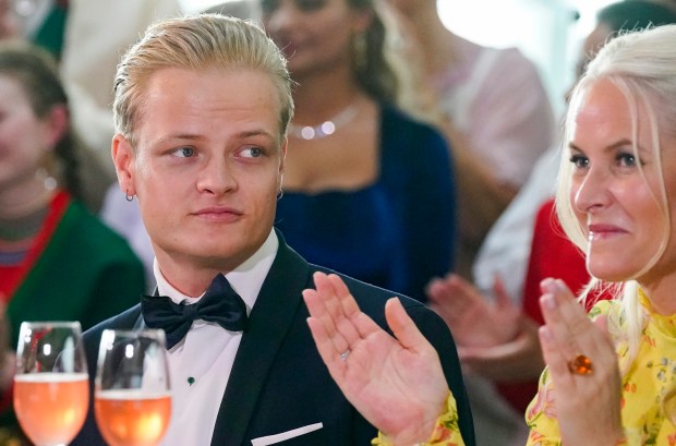 a man in a tuxedo sits next to a woman who is clapping