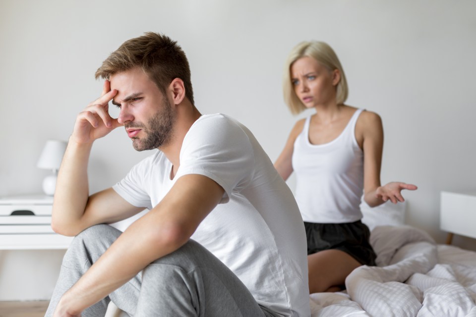 a man sits on a bed while a woman sits behind him