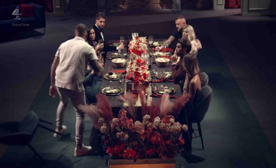 a group of people are sitting around a table with flowers and a sign that says brand new