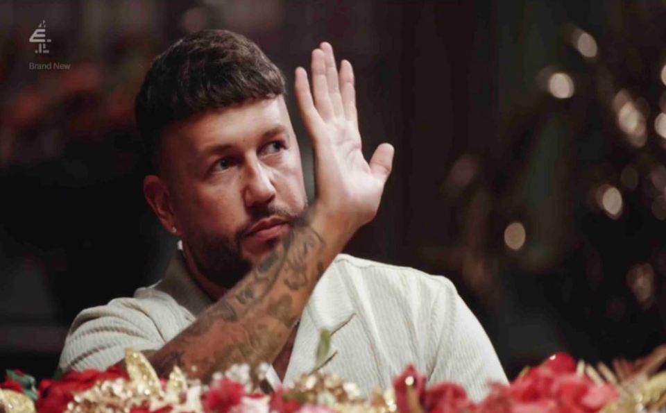 a man with a tattoo on his arm is sitting at a table with flowers