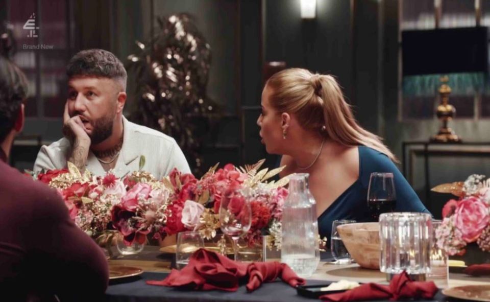 a man and a woman sit at a table with flowers and a sign that says brand new