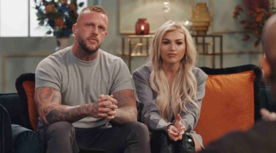 a man and a woman are sitting on a couch with their hands folded