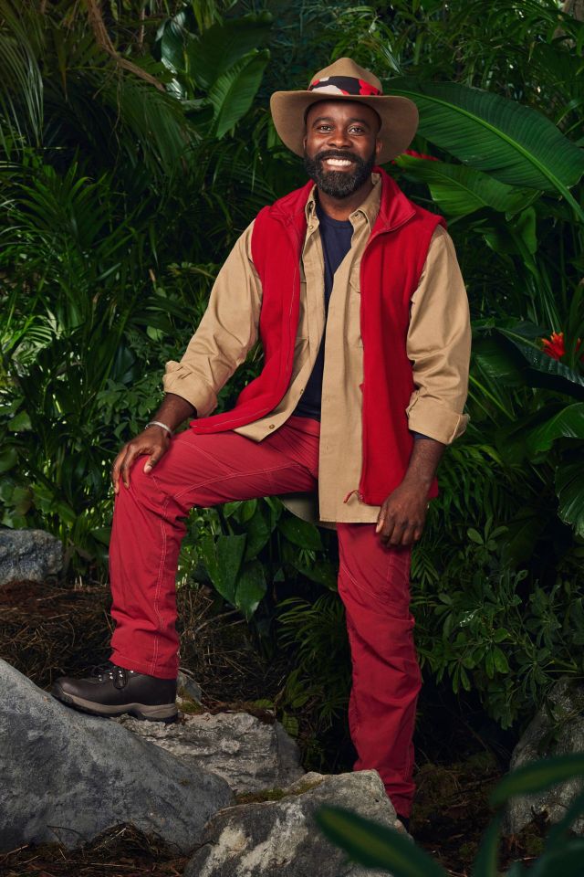 a man in a cowboy hat is sitting on a rock in the jungle