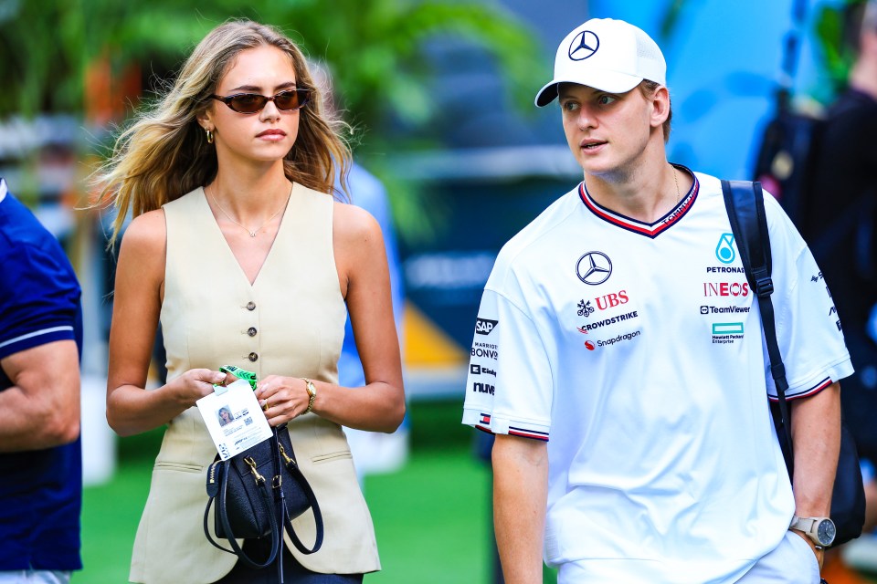 a man wearing a mercedes shirt stands next to a woman