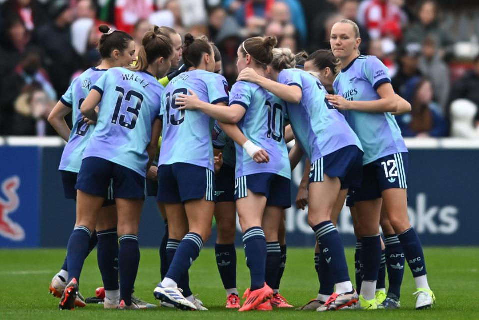 a group of female soccer players huddle together with one wearing the number 12