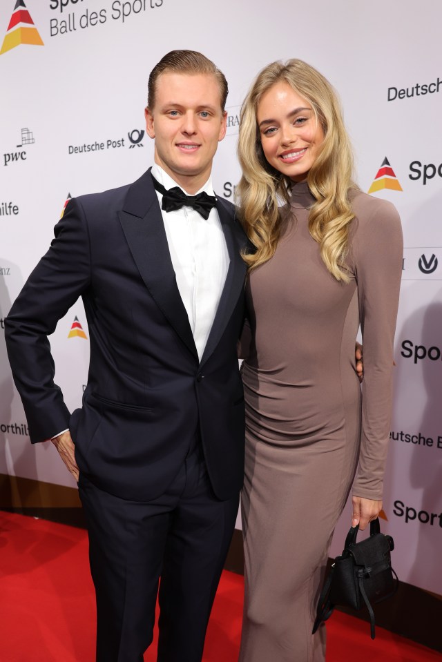 a man in a tuxedo and a woman in a dress pose on a red carpet