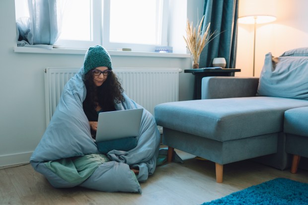 a woman wrapped in a blanket is using a laptop