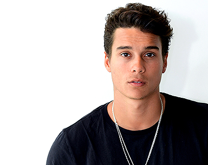 a young man wearing a black shirt and a silver chain around his neck