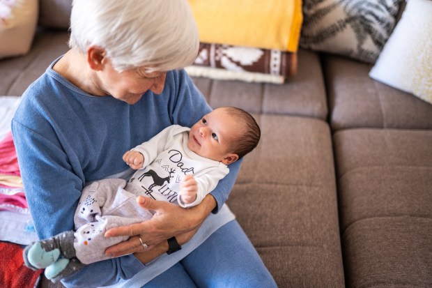 an older woman is holding a baby wearing a shirt that says dad