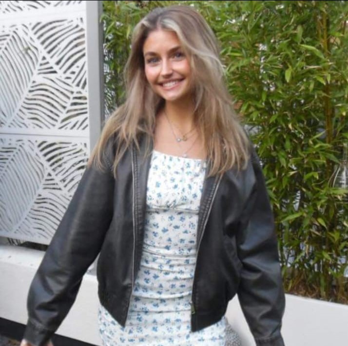 a woman wearing a black leather jacket and a white dress