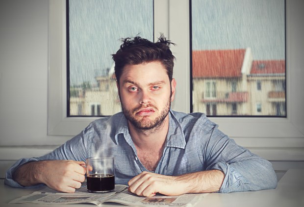 a man sits at a table with a cup of coffee and a newspaper